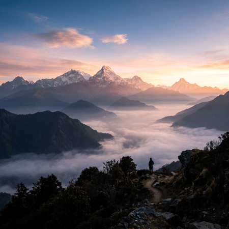 Hiker on mountain trail with misty valleys and snow-covered Himalayan mountains at sunrise