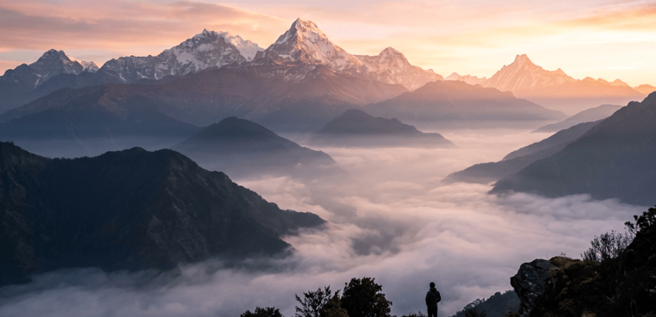 Hiker on mountain trail with misty valleys and snow-covered Himalayan mountains at sunrise